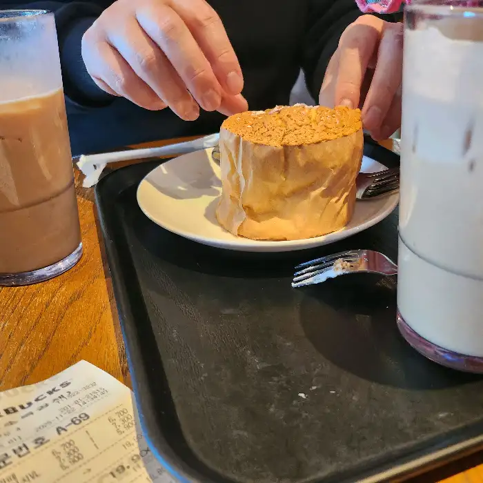 손이 빵 조각을 떼어내고 있는 모습과 음료 두 잔