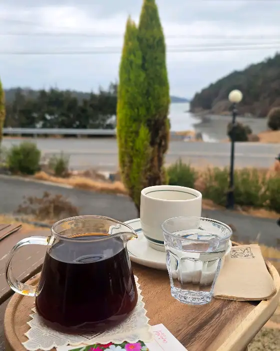 테이블 위에 놓인 커피 포트와 잔, 그리고 창밖 풍경