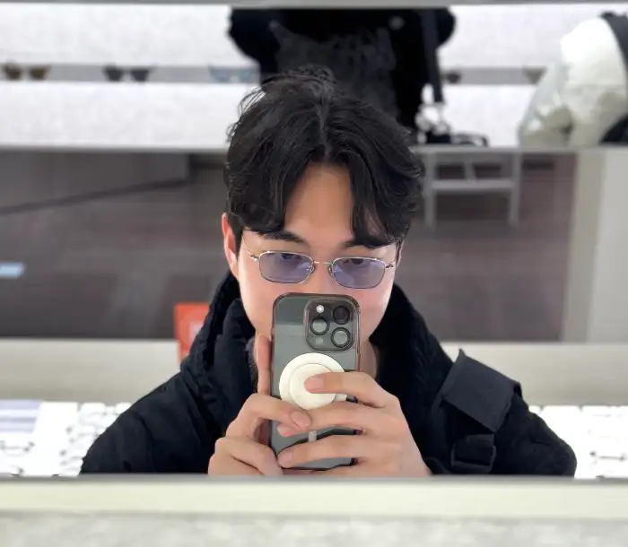 남자가 안경을 쓰고 휴대폰으로 셀카를 찍는 모습