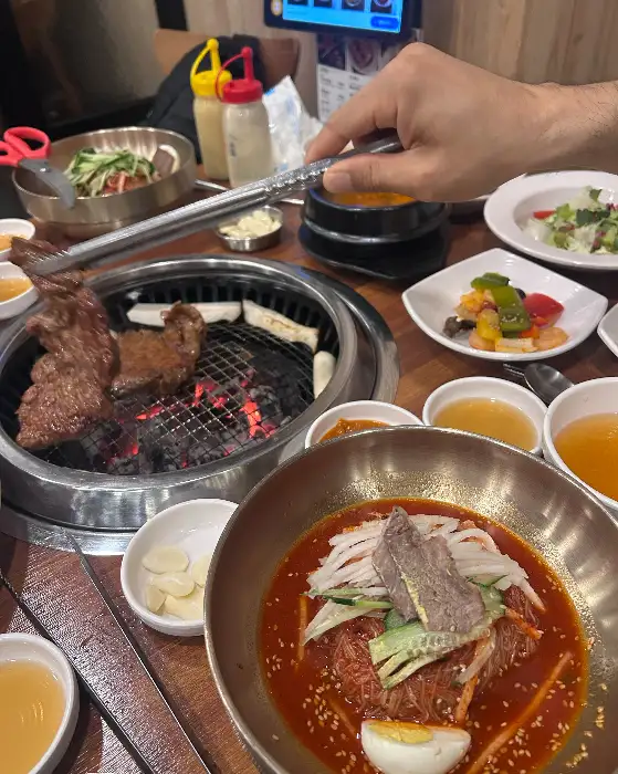 집게로 돼지갈비를 집어 숯불에 올리는 모습