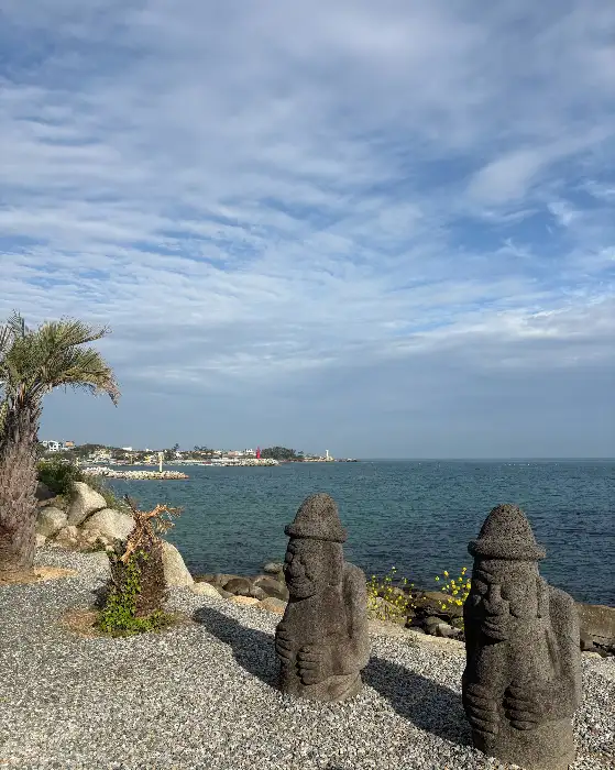 바다를 배경으로 놓인 돌 조각상과 야자수