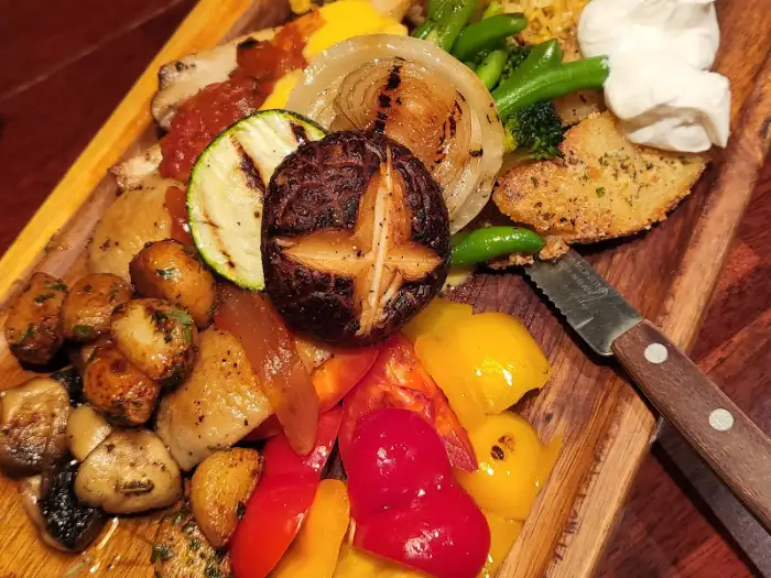 다양한 구운 채소와 버섯, 빵이 포함된 스테이크 플레이트