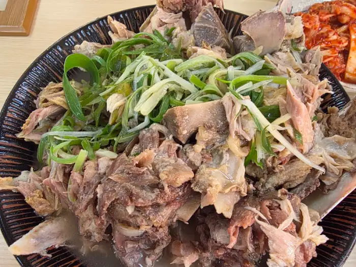 접짝뼈국에 큼지막한 돼지 등뼈와 파채가 듬뿍 올라가 있는 모습.