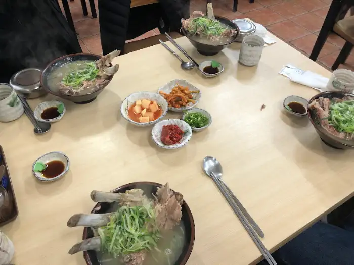 여러 개의 접시가 놓인 테이블 전체 모습. 접짝뼈국, 깍두기, 파절이 등이 보인다.