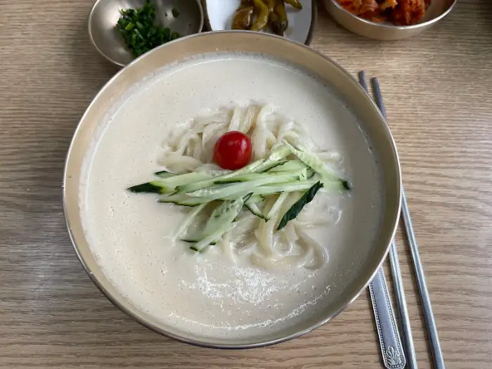 콩국수 클로즈업 사진. 뽀얀 국물과 얇은 면발, 고명이 선명하게 보입니다.