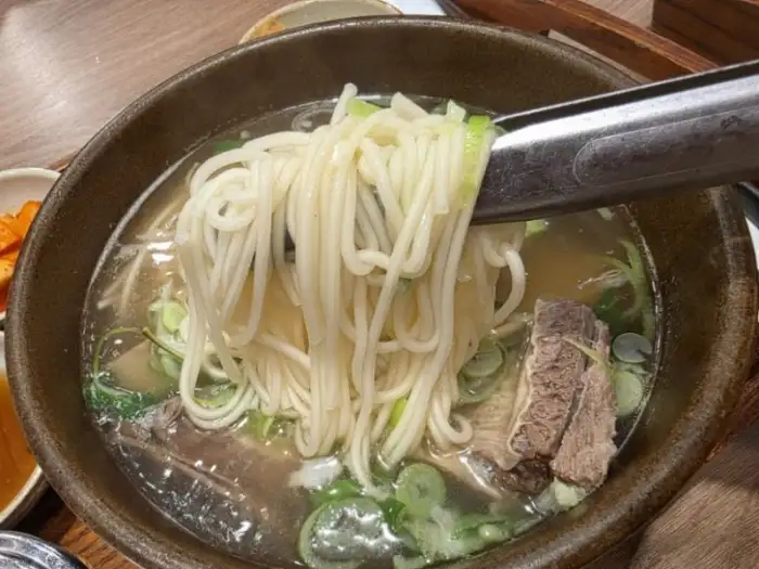 갈비탕에 큼지막한 갈비 조각이 부드럽게 발라지고 있는 모습