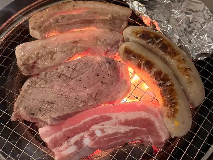 고기와 소시지, 버섯 등이 함께 구워지고 있는 숯불 바베큐 모습