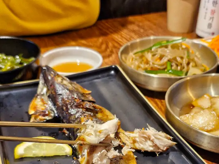 잘 구워진 고등어구이 한 토막을 젓가락으로 집고 있는 모습