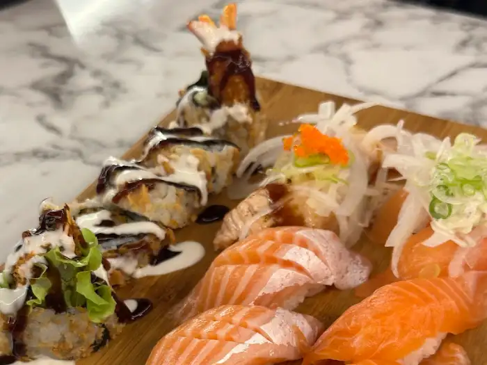 붉은 소스가 뿌려진 롤 초밥과 신선한 연어 초밥, 그리고 흰 살 생선 초밥의 클로즈업