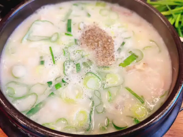 뽀얀 국물에 다진 파와 후추가 뿌려진 순대국밥의 근접 사진.