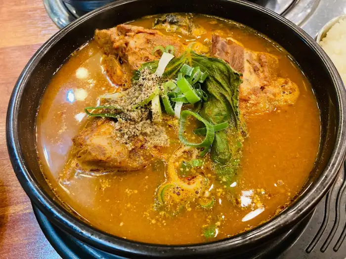 푸짐한 뼈해장국 사진. 큼지막한 뼈와 건더기, 파채 등이 얹어져 있다.