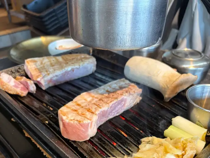 그릴 위에서 익어가고 있는 흑돼지 삼겹살과 새송이버섯, 곁들임 채소