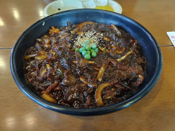 쟁반 짜장 위에 완두콩이 몇 알 올라가 있는 모습