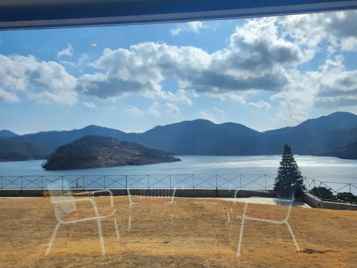 넓은 창을 통해 보이는 옥정호와 산자락의 풍경, 전경에는 야외 좌석과 함께 푸른 잔디밭이 펼쳐져 있다.