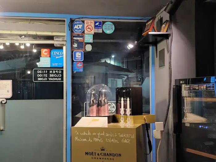 가게 입구 모습, 다양한 인증 스티커와 함께 샴페인 병이 놓여 있다.