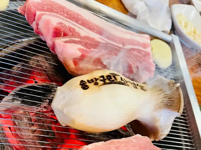 숯불 위에서 익어가는 삼겹살과 버섯