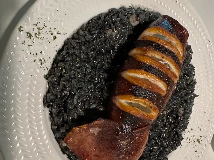 먹물 리조또와 오징어 요리, 검은색 리조또와 윤기 나는 오징어가 대비됨