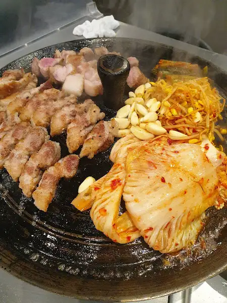 삼겹살, 김치, 콩나물, 마늘이 함께 구워지는 불판