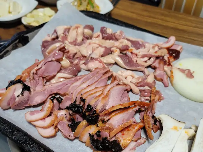 불판 위에 올라간 오리로스, 부추, 팽이버섯