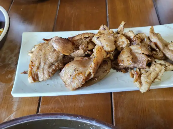 나무 테이블 위에 놓인 하얀 접시에 담긴 먹음직스러운 닭고기 요리