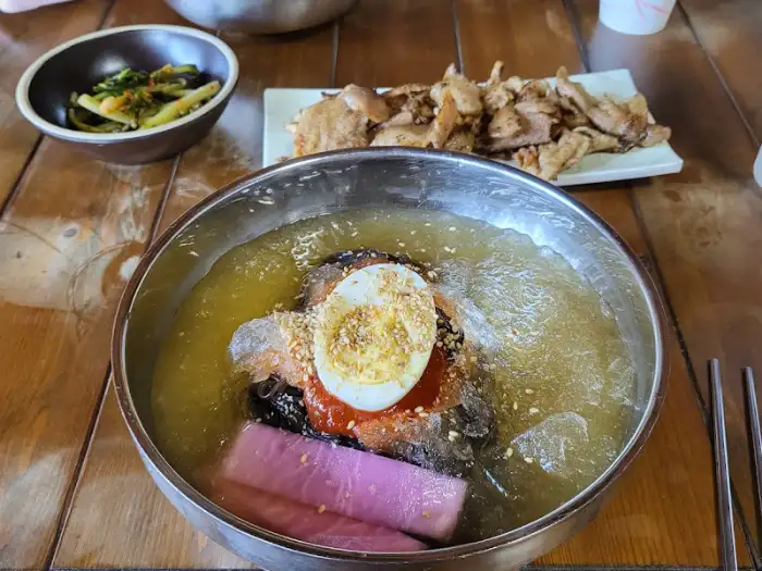 놋그릇에 담긴 시원해 보이는 냉면, 계란 지단, 오이, 무절임 등이 고명으로 올라가 있습니다.