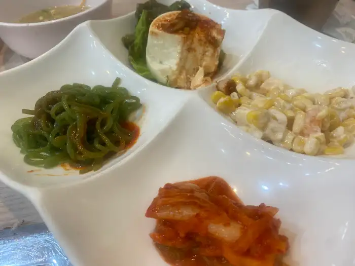 네 칸으로 나뉜 앞접시에 담긴 다양한 밑반찬 - 클로즈업 샷