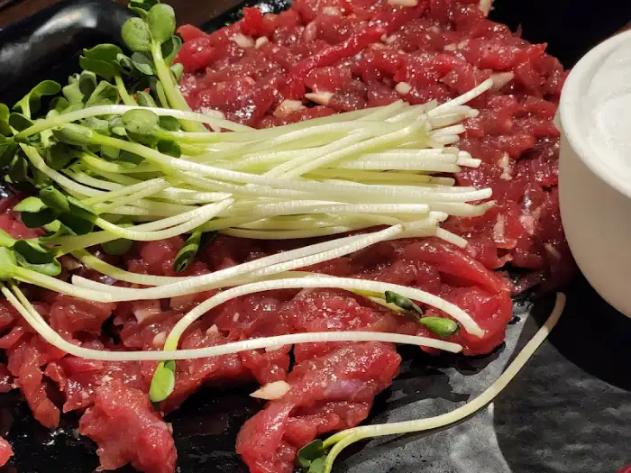 육회 위에 콩나물과 파 등의 채소를 얹은 모습