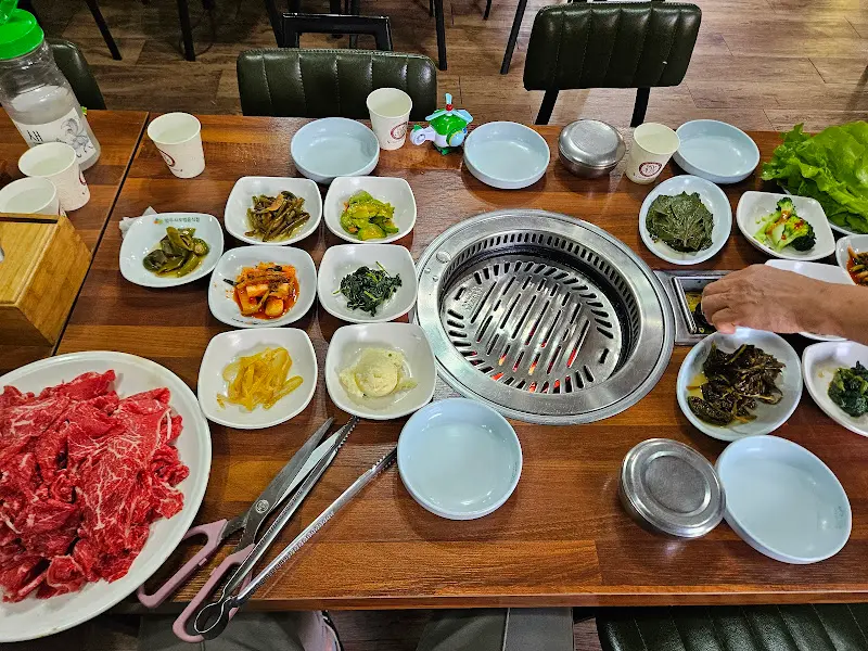 테이블 가득 차려진 밑반찬과 숯불구이 불판