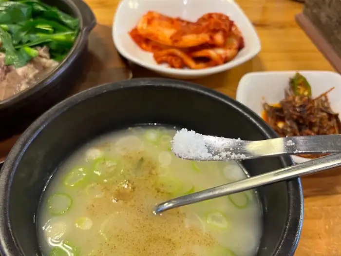 따로국밥에 소금 간을 하고 있는 모습.