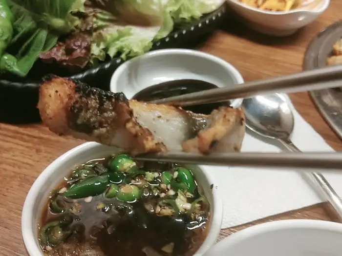 스테이크처럼 두툼한 고기 한 점을 소스에 찍어 먹는 모습