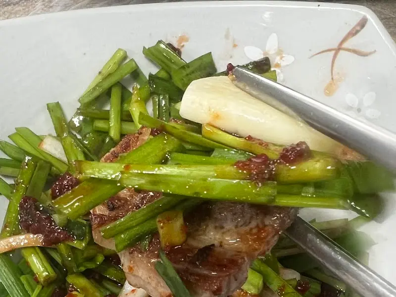 잘 구워진 삼겹살 위에 신선한 쪽파가 듬뿍 올려진 모습