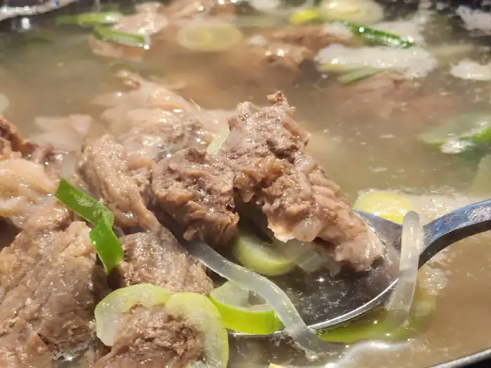 육수 속 고기 조각과 파, 무 등이 보이는 클로즈업 사진