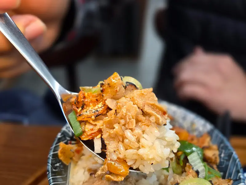 숟가락 위에 밥과 돼지고기를 함께 올려 먹는 모습. 불향이 느껴지는 달콤 짭짤한 양념이 밥과 조화롭게 어우러진다.