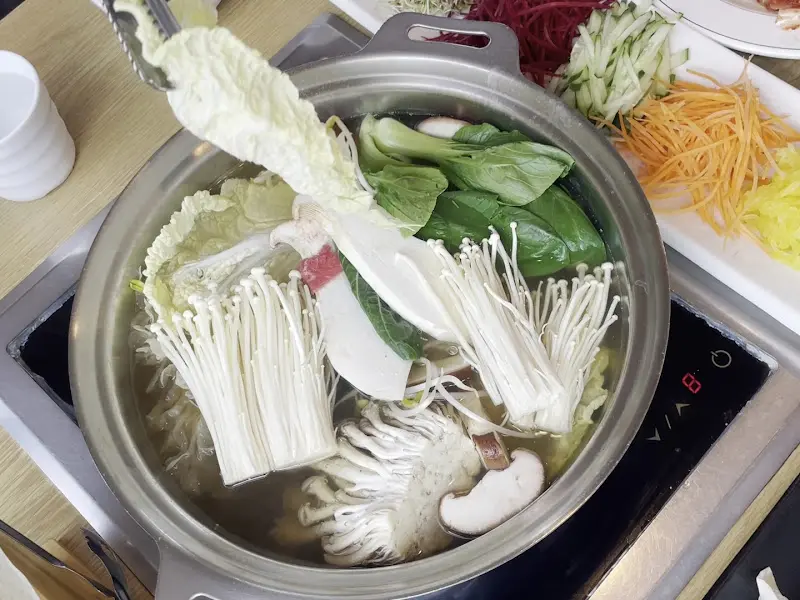 샤브샤브 육수에 버섯과 야채를 넣는 모습