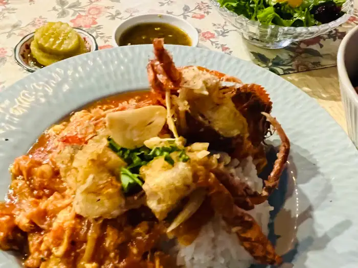 붉은색 커리 소스를 곁들인 게 요리와 밥