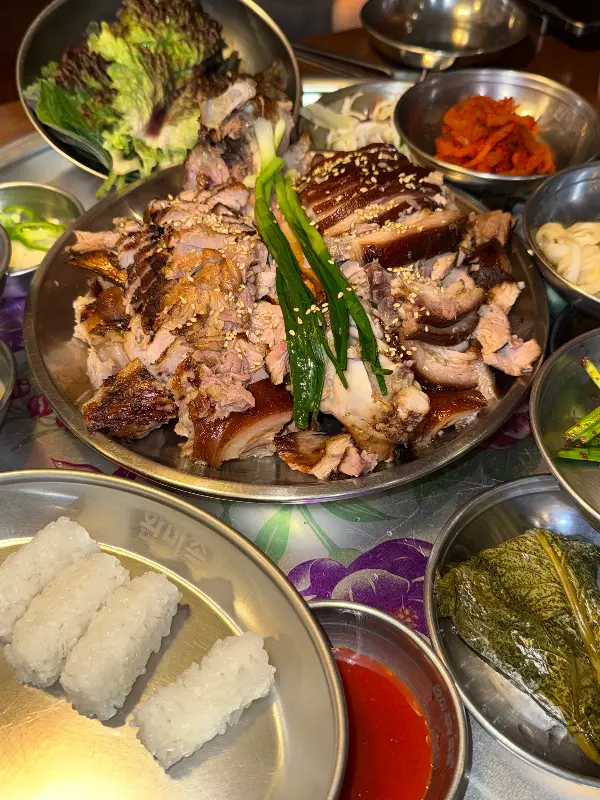 윤기가 흐르는 족발과 다양한 곁들임 찬들이 푸짐하게 담긴 쟁반