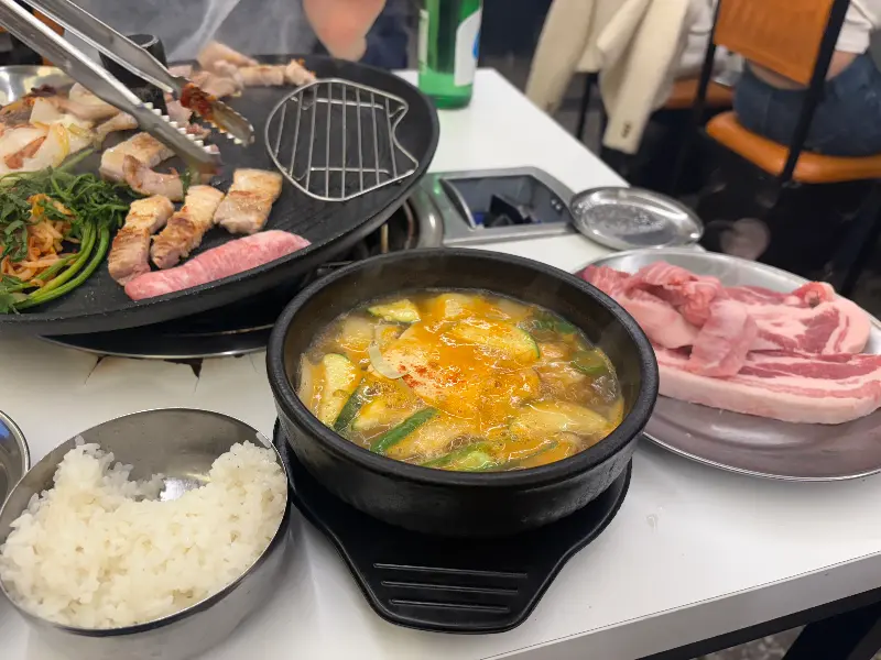 잘 익은 삼겹살과 된장찌개, 밥 한 공기가 놓여있는 푸짐한 상차림