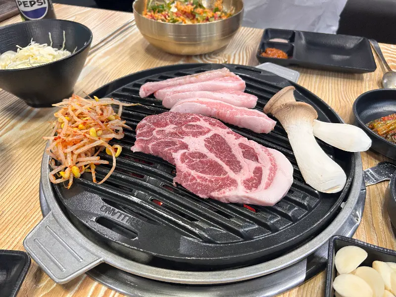 불판 위에 올려진 삼겹살과 버섯