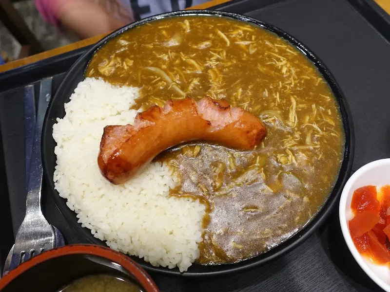 카레라이스 위에 큼지막한 소시지 토핑이 올려져 있다.