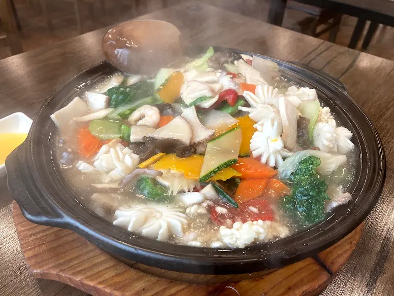 테이블 위에서 김이 모락모락 피어오르는 해물 누룽지탕