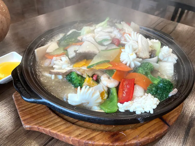 나무 받침대 위에 올려진 해물 누룽지탕 뚝배기