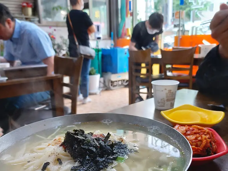 테이블에 놓인 칼국수, 김치, 단무지