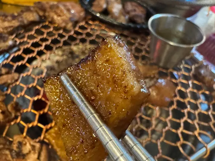 집게로 집어 올린 노릇하게 구워진 돼지 껍데기