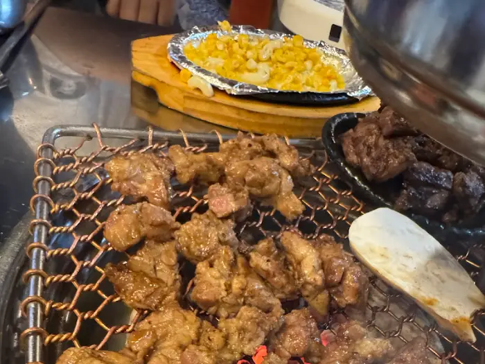 숯불 위에서 익고 있는 뽈살과 곁들임 음식