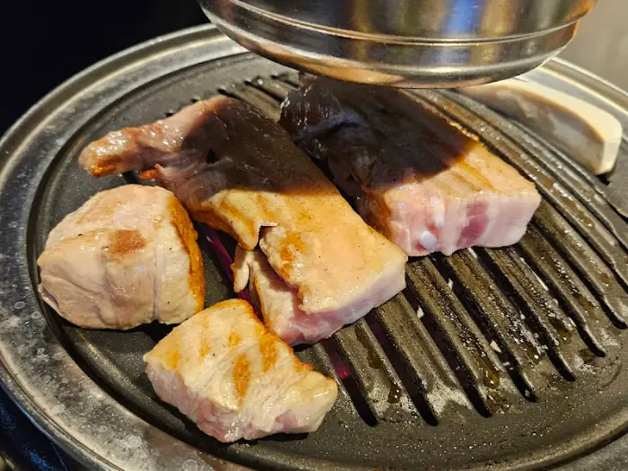 금속 재질의 둥근 불판 위에서 익어가는 두툼한 고기 덩어리들