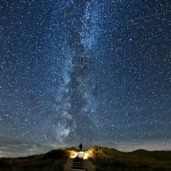 밤하늘의 은하수와 그 아래 계단을 오르는 사람