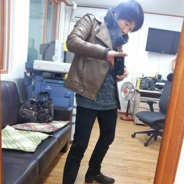 깔끔한 옷차림의 남자가 거울을 보며 휴대폰으로 사진을 찍는 모습