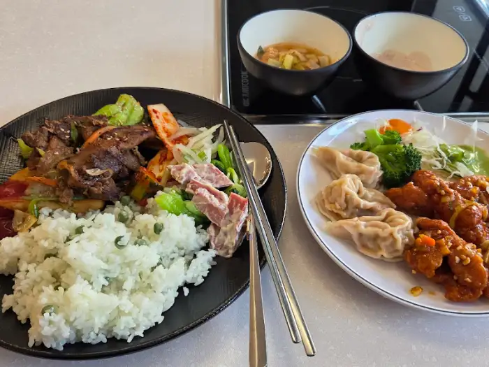 한 접시에 담긴 밥, 고기, 채소 볶음과 다른 접시에 담긴 튀김, 만두