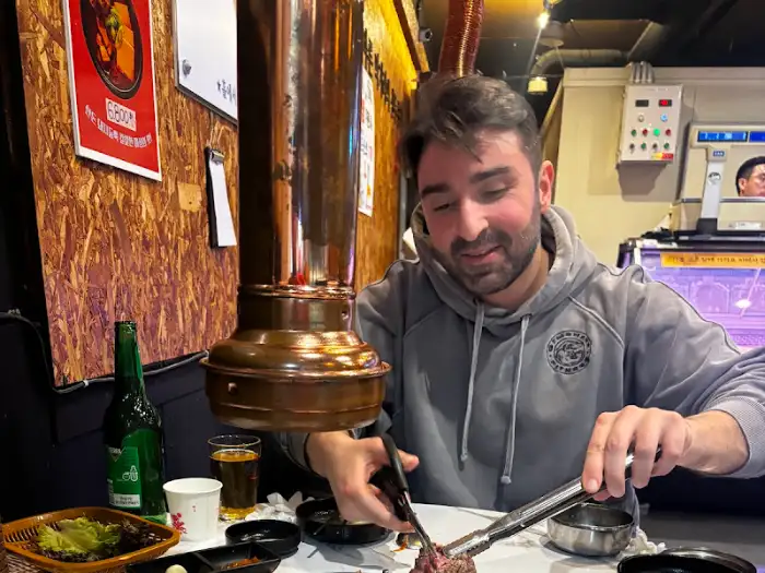 한 남자가 불판 앞에서 고기를 굽고 있는 모습