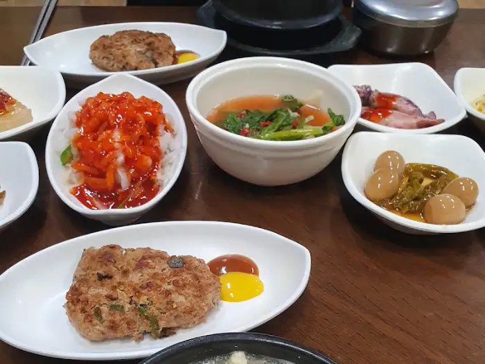 두부 스테이크, 붉은색 양념의 반찬, 야채가 든 찌개, 오징어 젓갈 등으로 보이는 음식들